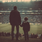 **father and son holding hands in a football stadium, they are far from the photo, fans in the background** - Image #2 <@450124934837043201>