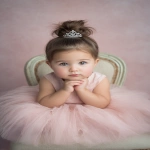 **baby girl styled with an elegant princess bun, smooth brown hair adorned with a tiny silver tiara, wearing a soft pink tulle dress, sitting in a decorative chair Shot with Canon EOS R8, 85mm lens, f/2.0, ISO 100, White Balance 5600K, Portrait Studio Setup --ar 2:3 --v 7.0** - Image #3 <@888546328244801596>
