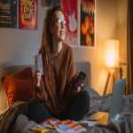 **a cheerful young woman sitting on a cozy bed, holding concert tickets in one hand and a black calculator in the other, open laptop on the bed showing budget spreadsheet, budget planner notebook and colorful concert ticket flyers in front of her, music posters on the wall (Pop Tour, Live in Concert, Music Festival), warm ambient lighting from a table lamp, friendly and relaxed atmosphere, photorealistic style --ar 16:9 --v 7.0 --q 2 --raw** - Image #4 <@1192072662005059597>