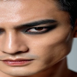 **full-face portrait of a fashionable 30-year-old Taiwanese man, long-shaped face, fair pale skin, thick eyebrows, large expressive double-lidded eyes, and naturally full lips, with softly contoured cheeks not sunken; styled with bold high-fashion smokey eye makeup in deep gray and black tones, paired with glossy lip color for a striking contrast; contemporary hairstyle with clean lines, cinematic editorial lighting highlighting makeup and hair details, blurred neutral background, sharp focus on facial features, refined fashion magazine aesthetic, no text, no watermark --ar 9:16** - Image #3 <@1090872516857299025>