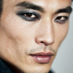 **full-face portrait of a fashionable 30-year-old Taiwanese man, long-shaped face, fair pale skin, thick eyebrows, large expressive double-lidded eyes, and naturally full lips, with softly contoured cheeks not sunken; styled with bold high-fashion smokey eye makeup in deep gray and black tones, paired with glossy lip color for a striking contrast; contemporary hairstyle with clean lines, cinematic editorial lighting highlighting makeup and hair details, blurred neutral background, sharp focus on facial features, refined fashion magazine aesthetic, no text, no watermark --ar 1:1** - Image #2 <@1090872516857299025>