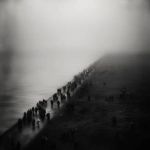 **An evocative and minimalist digital artwork, wide aerial shot, with a dark, monochromatic aesthetic, maintaining the style of the previous designs. The composition depicts a vast, dense crowd of silhouetted figures moving along a narrow strip of land, bordered by a muted, dark sea on one side and a barren, shadowy landscape on the other. The sheer number of individuals creates a sense of overwhelming displacement. The sky is overcast and a uniform dark tone, contributing to a feeling of somberness and uncertainty. The figures appear small and almost indistinguishable, emphasizing the scale of the exodus and their collective vulnerability. The scene evokes a powerful sense of forced migration and the loss of place, rendered with a stark and uncluttered visual style --v 7.0** - Upscaled by <@1032195406119043132> (fast)