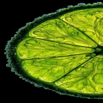 **ultra-close macro of a key lime slice, positioned tight against the right margin, about two-thirds visible, left side empty black negative space; bright neon-green translucent pulp, glowing under strong backlight, thin rind with subtle grain; natural micro-droplets (0.3-0.8mm) along rind edge, none floating; clinical food macro lighting, polarizing filter, sharp texture of juice vesicles, hyperreal color contrast --ar 59:128 --v 7.0 --q 2 --p mt1858g** - Image #4 <@762546997382348820>