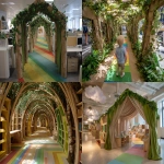 **The tunnel structure is made of thin support poles from a garden arch measuring 1.5 meters in height, 1.2 meters in width, and 5 meters in depth. Inside the entrance of the cardboard arch, the exterior is decorated with a forest interior, and a path made of thin rainbow-colored vinyl tape is depicted on the floor.a cotton cloud canopy, and an interior resembling library shelves mapped onto cardboard at the end of the forest. A children's attraction interacting with a server station is installed by covering office desks and displays with fabric, placing them in the pathways between desks, removing desk chairs to create pathways, and masking the lower parts of desks with green curtains. Cardboard guardrails are installed up to waist height, creating a bright and cheerful atmosphere. --ar 4:3** - <@580349603761750038> (fast)