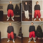 **A young handsome tan skinned white man with dirty blonde wavy short hair dressed in a Y2K Cholo gangster style, wearing a black long sleeve Dickies work shirt and extremely baggy, extra-long, 3XL plain long red and black Jordan basketball shorts. His shorts are very long and go down to his ankles and feet. He is wearing Nike Cortez shoes in his house by a Christmas tree --v 7.0** - Remix (Strong) by <@1061360796438900746> (fast)