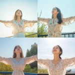 **A young and beautiful Korean woman standing outdoors, arms spread wide, basking in the warm sunlight. She is wearing a light floral-patterned blouse, exuding joy and a carefree spirit. The background includes a clear blue sky, subtle greenery, and a simple railing, emphasizing a sense of openness and freedom. The atmosphere is uplifting, natural, and serene, with soft lighting enhancing her youthful and vibrant appearance. Cinematic and realistic style.** - <@656836270752006172> (fast)