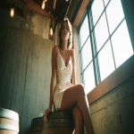 **"Candid Wide-angle shot of Glamorous woman in silk slip dress casually perched atop a whiskey barrel in a hallway near the bathroom of a restored distillery, ambient Edison bulbs above, concrete walls, captured on Canon AE-1 with 50mm f/1.8, shot on Kodak Ektar 100, vibrant but slightly washed vintage tones, open-air California light, natural lens flares, mid-century resort-style fashion, Slim Aarons composition, crisp but relaxed vibe v 6.0 --ar 16:9 --raw --v 7.0** - Upscaled by <@1090364262091866152> (fast)