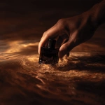 **shadow of masculine hands pulling a small square black glass perfume bottle out of a dark poool of amber colored sensorial oil. The light is diffused and low, revealing texture only in suggestion, not in shine. Every tone sits within a warm spectrum of sienna and tobacco brown. The image feels cinematic and meditative, like the opening frame of a luxury skincare film matte, understated, timeless. ar 21:9 style raw v 6 q 2 uplight low contrast dark tone** - Image #4 <@1137240197814288404>