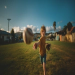 **Image from slightly above eye level: a 10-year-old boy wearing blue shorts and an ochre t-shirt stands on a lush green park lawn, mid-action as he throws a baseball directly toward the viewer. A baseball glove is on his hand, and the ball floats mid-air above him. He is looking directly at the camera. Natural sunlight with soft shadows illuminates the scene. The background features a clear blue summer sky, distant trees, and buildings along the horizon. Full-body view, professional color grading, clean sharp focus, no grain, cinematic quality. Shot with a Sony Alpha A7 III and Zeiss ultra-macro lens, f/2.8 aperture, high resolution:: --aspect 16:9 --s 250** - Image #4 <@1220830039520841890>
