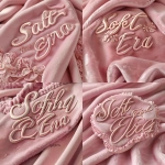 **ultra-realistic typography logo that reads "Soft Girl Era", in a graceful hand-lettered cursive script, delicate yet bold, with smooth rounded strokes, made of plush suede fabric, subtle stitching detail, resting on a soft-focus powder-pink suede background, natural diffused studio lighting, high-resolution macro texture, creamy pastel tones, dreamy feminine aesthetic, no symbols, no frames, just the elegant suede text on suede backdrop --ar 1:1 --v 6.0 --s 250 --raw** - Variations (Strong) by <@1070056867990085722> (fast)