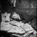 **abrahm vermont, un escritor adulto de 30 años en 1915 en rosario duermiendo acostado en el piso de noche. se tapa con diarios porque no tiene frasada. cubierto por los ejemplares de diario como sabana. 'the vols stimme' su diario escrito en idish litografiado. Vive entre sus palabras en su cuarto muy pequeño de conventillo y con pocas cosas, para escribir y litografia. Escena de pelicula de thirller moderno ambientado en 1910 pero con la calidad actual de cine profesional. Vermont es dejado, tiene bigote largo pero sin barba y poco pelo y un poco gordo, viste formal, pero gastado.** - Image #4 <@985959374633717780>