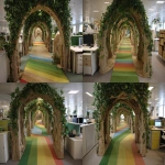 **The tunnel structure is made of thin support poles from a garden arch measuring 1.5 meters in height, 1.2 meters in width, and 5 meters in depth. Inside the entrance of the cardboard arch, the exterior is decorated with a forest interior, and a path made of thin rainbow-colored vinyl tape is depicted on the floor.a cotton cloud canopy, and an interior resembling library shelves mapped onto cardboard at the end of the forest. A children's attraction interacting with a server station is installed by covering office desks and displays with fabric, placing them in the pathways between desks, removing desk chairs to create pathways, and masking the lower parts of desks with green curtains. Cardboard guardrails are installed up to waist height, creating a bright and cheerful atmosphere. --ar 4:3** - Variations (Strong) by <@580349603761750038> (fast)