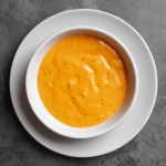 **make a delicious flat lay top down photo of bang bang sauce which is a thick creamy orange sauce with no herbs or spices in a white bowl on a white plate --q 2** - Image #2 <@310557554851971073>