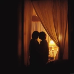 **A romantic couple sharing an intimate moment behind soft golden curtains, warmly lit by a cozy floor lamp, wrapped together in a blanket, silhouetted gently, dreamy and tender atmosphere, early morning or twilight glow, peaceful indoor setting, shallow depth of field, cinematic lighting, vintage color grading, 35mm film style, subtle grain, emotional storytelling, soft focus, style cinematic --v 7.0** - Upscaled by <@1331627685406965792> (fast)
