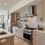 **interior design of a model unit showing the kitchen area. linear layout. all stainless appliances. chimney type range hood. stainless steel countertop with oak cabinets** - Image #2 <@1231814052913877045>