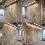 **A photo of an intricate, hand-painted wallpaper with faded gold and silver designs on the wall in an office building. The texture is rough concrete with visible sanded edges. There's an LED light bar above it that casts a soft glow over its surface. A windowless corner wall is on one side. In the background, there's another wallpaper design that looks similar but less detailed. It has more colors and patterns. The room also features white square lighting fixtures on the walls, creating subtle shadows on the ceiling. --ar 32:23** - Variations (Strong) by <@1313000520759377972> (fast)