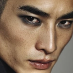 **full-face portrait of a fashionable 30-year-old Taiwanese man, long-shaped face, fair pale skin, thick eyebrows, large expressive double-lidded eyes, and naturally full lips, with softly contoured cheeks not sunken; styled with bold high-fashion smokey eye makeup in deep gray and black tones, paired with glossy lip color for a striking contrast; contemporary hairstyle with clean lines, cinematic editorial lighting highlighting makeup and hair details, blurred neutral background, sharp focus on facial features, refined fashion magazine aesthetic, no text, no watermark --ar 1:1** - Image #1 <@1090872516857299025>
