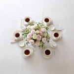 **simple, yet elegant tabletop, view is looking down on it, elegant ivory linen tablecloth, centerpiece of pink and white roses, six (6) steaming coffee cups symmetrically placed at each of the six (6) table settings** - Image #1 <@1141845422852280493>