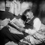 **abrahm vermont, un escritor adulto de 30 años en 1915 en rosario duermiendo acostado en el piso de noche. se tapa con diarios porque no tiene frasada. cubierto por los ejemplares de diario como sabana. 'the vols stimme' su diario escrito en idish litografiado. Vive entre sus palabras en su cuarto muy pequeño de conventillo y con pocas cosas, para escribir y litografia. Escena de pelicula de thirller moderno ambientado en 1910 pero con la calidad actual de cine profesional. Vermont es dejado, tiene bigote largo pero sin barba y poco pelo y un poco gordo, viste formal, pero gastado.** - Image #3 <@985959374633717780>