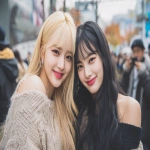 **a photo of two young k-pop idol girls in the city street, one blonde with bangs and long hair wearing stylish elegant autumn fashion with exposed décolleté (light knit or off-shoulder top with skirt or light jacket), the other a black-haired girl in modern chic autumn attire (not too heavy, slightly revealing neckline for a refined look), both smiling at the camera. the background is blurred cityscape to emphasize their expressions and interaction. no hats, natural hairstyle. --ar 3:2 --v 7.0** - Image #3 <@439649665210908673>