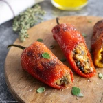**<https://s.mj.run/LuDWu39peyE> <https://s.mj.run/-sPvWyoU1oU> <https://s.mj.run/45GmJjmodfk> Hyper-realistic close-up of whole Neapolitan-style stuffed sweet peppers (peperoni imbottiti), golden and blistered from frying, resting on a rustic kitchen countertop. The peppers are filled to the top with a mixture of bread, anchovies, herbs, crushed walnuts, garlic, tomato, and grated cheese. Some stuffing is slightly visible at the opening. A bit of olive oil glistens on the skin, and light frying marks enhance the roasted look. Warm, natural lighting from a nearby window highlights the textures and vibrant colors. Background includes a wooden cutting board, scattered herbs, and a casual Southern Italian kitchen ambiance.** - Image #4 <@1277569890588557353>