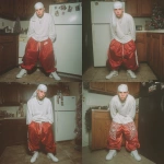 **A young handsome tan skinned teenage white man wearing a white Durag dressed in a Y2K Cholo gangster style, wearing a long sleeve white t shirt and extremely baggy, extra-long, 3XL plain long red and white Jordan basketball shorts. His shorts are very long and go down to his ankles and feet. He is wearing a white Durag around his head. He is wearing Nike Cortez shoes standing in his house by a Christmas tree --v 7.0** - Variations (Strong) by <@1061360796438900746> (fast)