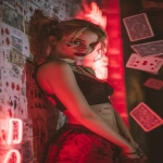 **Harley Quinn leaning against a wall of neon red signs, mischievous grin, red lipstick and smudged makeup, holding a deck of playing cards that scatter in the air, glowing red atmosphere, dramatic and suggestive, cinematic composition, space for lyrics --ar 9:16 --v 7.0** - Image #2 <@257221362568003584>