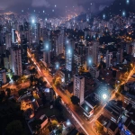 **A wide horizontal view of downtown Belo Horizonte, Brazil, focusing on a specific urban block with public street parking. Highlight smart city elements: connected parking spots with sensors, glowing digital markers indicating availability, real-time data overlays, augmented reality navigation elements floating above the streets. Include buildings from the city center, subtle hills in the background (Serra do Curral), and urban signage. Emphasize horizontal composition, clean and futuristic urban design. Color palette: deep gray, moss green, burnt orange. Lighting: early evening with soft tech glow. No people, no cars. Visual style: semi-realistic, with minimalist tech UI elements. --ar 16:9 --v 6.0** - Image #1 <@361336964084924446>