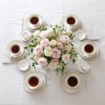 **simple, yet elegant tabletop, view is looking down on it, elegant ivory linen tablecloth, centerpiece of pink and white roses, six (6) steaming coffee cups symmetrically placed at each of the six (6) table settings** - Image #4 <@1141845422852280493>