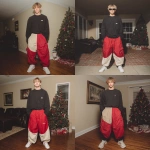 **A young handsome tan skinned white man with dirty blonde wavy short hair dressed in a Y2K Cholo gangster style, wearing a black long sleeve Dickies work shirt and extremely baggy, extra-long, 3XL plain long red and black Jordan basketball shorts. His shorts are very long and go down to his ankles and feet. He is wearing Nike Cortez shoes in his house by a Christmas tree --v 7.0** - Remix (Strong) by <@1061360796438900746> (fast)